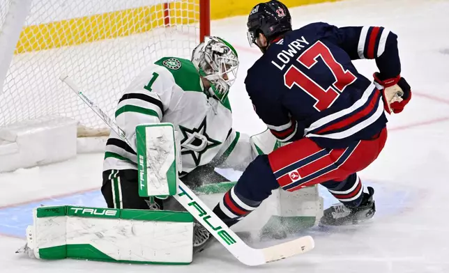 Dallas Stars' goaltender Casey DeSmith (1) makes a save on Winnipeg Jets' Adam Lowry (17) during the third period of their NHL hockey game in Winnipeg, Tuesday, Dec. 9, 2025. (Fred Greenslade/The Canadian Press via AP)