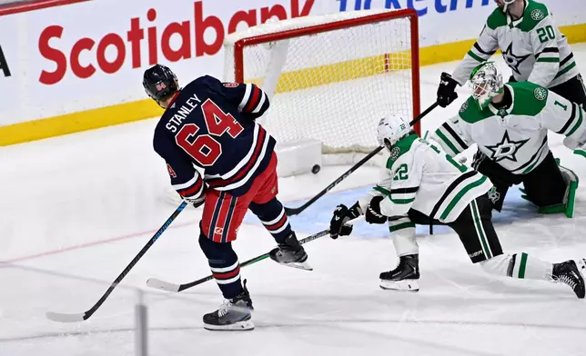 Winnipeg Jets' Logan Stanley (64) scores on Dallas Stars' goaltender Casey DeSmith (1) during the third period of their NHL hockey game in Winnipeg, Tuesday, Dec. 9, 2025. (Fred Greenslade/The Canadian Press via AP)