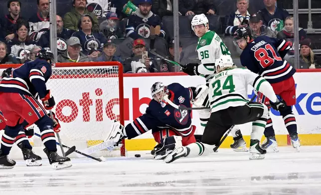 Dallas Stars' Roope Hintz (24) scores on Winnipeg Jets goaltender Eric Comrie (1) during the second period of an NHL hockey game in Winnipeg, Manitoba, Tuesday, Dec. 9, 2025. (Fred Greenslade/The Canadian Press via AP)