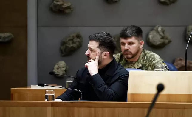 Ukraine's President Volodymyr Zelenskyy, front, attends a parliament session in The Hague, Netherlands, Tuesday, Dec. 16, 2025. (Robin van Lonkhuijsen/Pool Photo via AP)