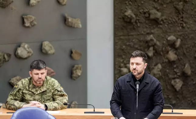 Ukraine's President Volodymyr Zelenskyy, right, delivers a speech during a parliament session in The Hague, Netherlands, Tuesday, Dec. 16, 2025. (Robin van Lonkhuijsen/Pool Photo via AP)