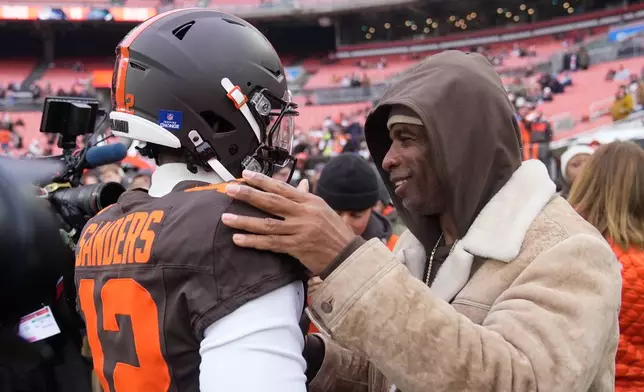 Cleveland Browns quarterback Shedeur Sanders (12) visits with his father Deion Sanders, right, during warmups before an NFL football game against the Tennessee Titans in Cleveland, Sunday, Dec. 7, 2025. (AP Photo/Sue Ogrocki)