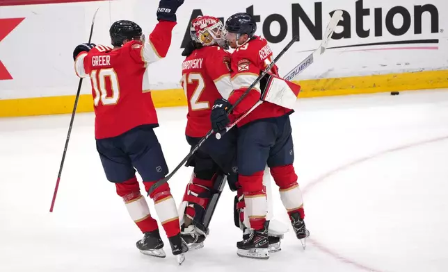 Florida Panthers goaltender Sergei Bobrovsky, center, celebrates with center Sam Reinhart, right, and left wing A.J. Greer (10) after making the winning save during overtime of an NHL hockey game against the Carolina Hurricanes, Friday, Dec. 19, 2025, in Sunrise, Fla. (AP Photo/Jim Rassol)