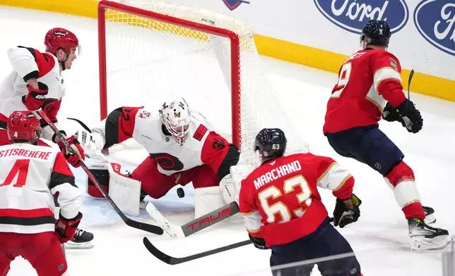 Carolina Hurricanes goaltender Brandon Bussi (32) makes a save against Florida Panthers center Sam Bennett as left wing Brad Marchand (63) closes in during overtime of an NHL hockey game, Friday, Dec. 19, 2025, in Sunrise, Fla. (AP Photo/Jim Rassol)