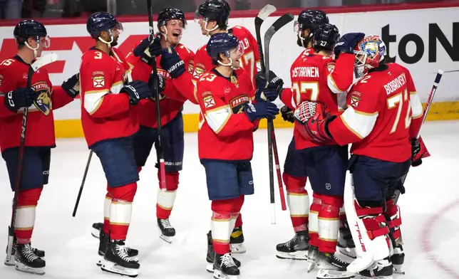 Florida Panthers goaltender Sergei Bobrovsky (72) celebrates with teammates after an NHL hockey game overtime win against the Carolina Hurricanes, Friday, Dec. 19, 2025, in Sunrise, Fla. (AP Photo/Jim Rassol)