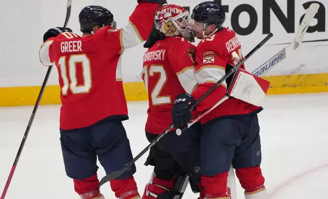 Florida Panthers goaltender Sergei Bobrovsky, center, celebrates with center Sam Reinhart, right, and left wing A.J. Greer (10) after making the winning save during overtime of an NHL hockey game against the Carolina Hurricanes, Friday, Dec. 19, 2025, in Sunrise, Fla. (AP Photo/Jim Rassol)