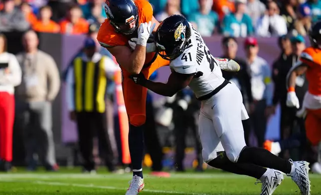 Jacksonville Jaguars defensive end Josh Hines-Allen (41) tackles Denver Broncos tight end Adam Trautman, left, during the first half of an NFL football game in Denver, Sunday, Dec. 21, 2025. (AP Photo/Jack Dempsey)