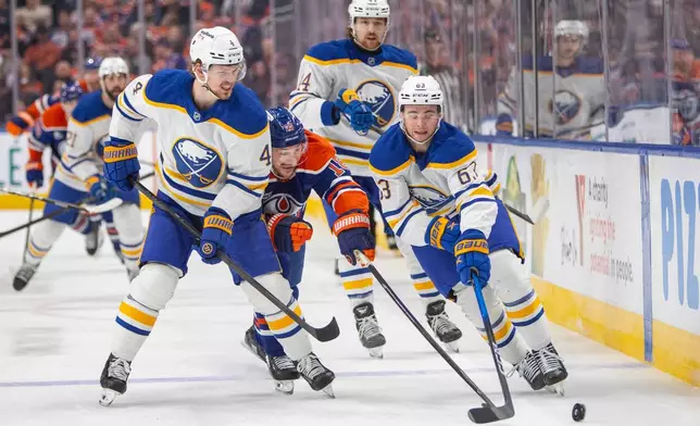 Buffalo Sabres b63, Bowen Byram (4) and Josh Dunne (44) outmaneuver Edmonton Oilers Zach Hyman (18) during second period NHL action in Edmonton, Tuesday, Dec. 9, 2025. (Amber Bracken/The Canadian Press via AP)