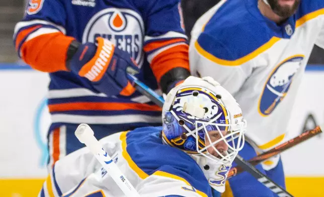 Buffalo Sabres goalie Alex Lyon (34) bats the puck away as Edmonton Oilers Adam Henrique (19) and Conor Timmins (21) look on during the second period of an NHL hockey game in Edmonton, Alberta, Tuesday, Dec. 9, 2025. (Amber Bracken/The Canadian Press via AP)