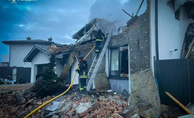 In this photo provided by the Ukrainian Emergency Service on Tuesday, Dec. 23, 2025, rescue workers put out a fire of a residential house destroyed by a Russian strike in Kyiv region, Ukraine. (Ukrainian Emergency Service via AP)