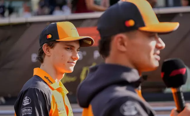 McLaren driver Oscar Piastri of Australia watches his team mate Lando Norris of Britain speak to media before the Abu Dhabi Formula One Grand Prix in Abu Dhabi, United Arab Emirates, Sunday, Dec. 7, 2025. (AP Photo/Darko Bandic)