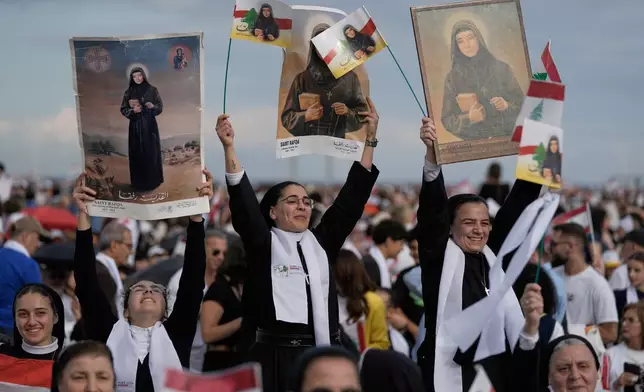Nuns hold up images of Lebanese Maronite nun Saint Rafqa as they wait for Pope Leo XIV to celebrate a Holy Mass at Beirut waterfront, in Beirut, Lebanon, Tuesday, Dec. 2, 2025. (AP Photo/Bilal Hussein)