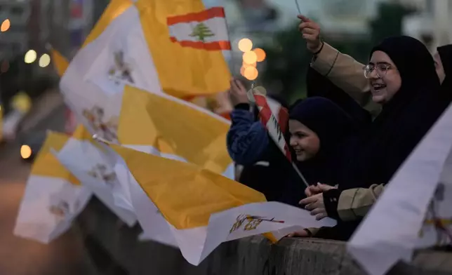 People wave Lebanese and Vatican flags as they wait to welcome Pope Leo XIV upon his arrival to Beirut, Lebanon, Sunday, Nov. 30, 2025. (AP Photo/Bilal Hussein)