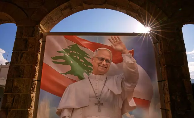 The sun peeks from behind a portrait of Pope Leo XIV before his arrival at the Psychiatric Hospital of the Cross in the town of Jal el-Dib, north of Beirut, Lebanon, Tuesday, Dec. 2, 2025. (AP Photo/Hassan Ammar)