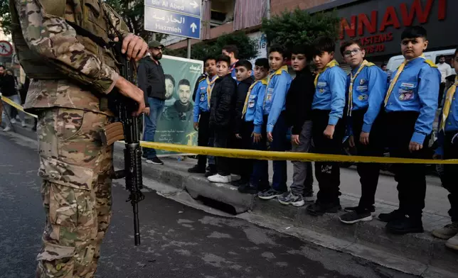 A Lebanese serviceman and youngsters wait to welcome Pope Leo XIV upon his arrival to Beirut, Lebanon, Sunday, Nov. 30, 2025. (AP Photo/Bilal Hussein)