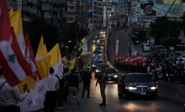 People wave Lebanese and Vatican flags as the motorcade with the Pope Leo XIV drives past upon his arrival to Beirut, Lebanon, Sunday, Nov. 30, 2025. (AP Photo/Bilal Hussein)