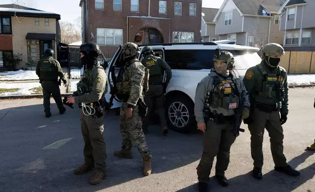 Federal immigration enforcement agents stand guard in front of their vehicles at West 33rd Street and South Ridgeway Avenue in the Little Village neighborhood of Chicago, Tuesday, Dec. 16, 2025. (Anthony Vazquez/Chicago Sun-Times via AP)