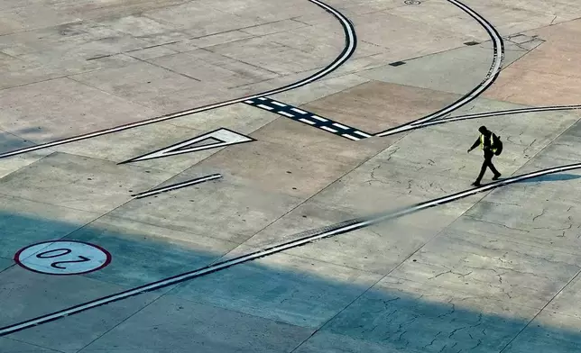 An airport official walks near a runway at the Indira Gandhi International Airport in New Delhi as several Indigo Airlines flights were cancelled or delayed, India, Thursday, Dec. 4, 2025. (AP Photo/Manish Swarup)