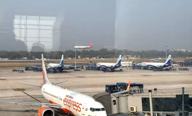 Three Indigo Airlines planes are seen through a glass window at the Indira Gandhi International Airport in New Delhi as several flights operated by the carrier were either cancelled or delayed, India, Thursday, Dec. 4, 2025. (AP Photo/Manish Swarup)