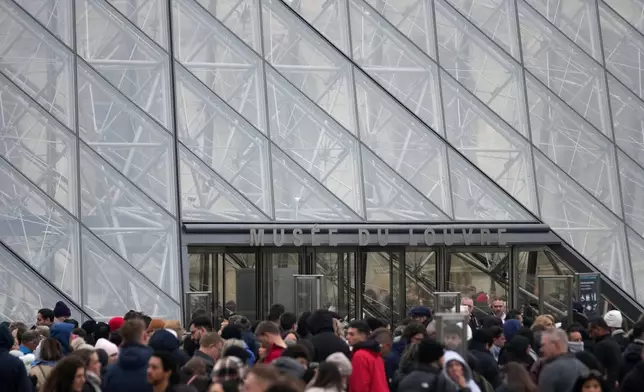 People wait at the entrance of the Louvre museum as employees were set to vote on whether to extend a strike that shut the world's most visited museum, as unions protest chronic understaffing, building deterioration and recent management decisions Wednesday, Dec. 17, 2025 in Paris. (AP Photo/Christophe Ena)