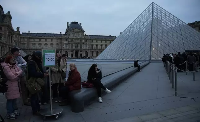 People wait at the entrance of the Louvre museum as employees were set to vote on whether to extend a strike that shut the world's most visited museum, as unions protest chronic understaffing, building deterioration and recent management decisions Wednesday, Dec. 17, 2025 in Paris. (AP Photo/Christophe Ena)