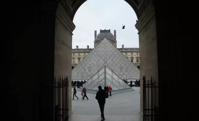 People wait at the entrance of the Louvre museum as employees were set to vote on whether to extend a strike that shut the world's most visited museum, as unions protest chronic understaffing, building deterioration and recent management decisions Wednesday, Dec. 17, 2025 in Paris. (AP Photo/Christophe Ena)