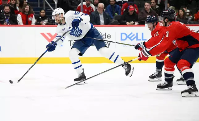 Toronto Maple Leafs center Nicolas Roy, left, shoots the puck past Washington Capitals left wing Anthony Beauvillier, second from right, and defenseman Matt Roy (3) during the second period of an NHL hockey game, Thursday, Dec. 18, 2025, in Washington. (AP Photo/Nick Wass)