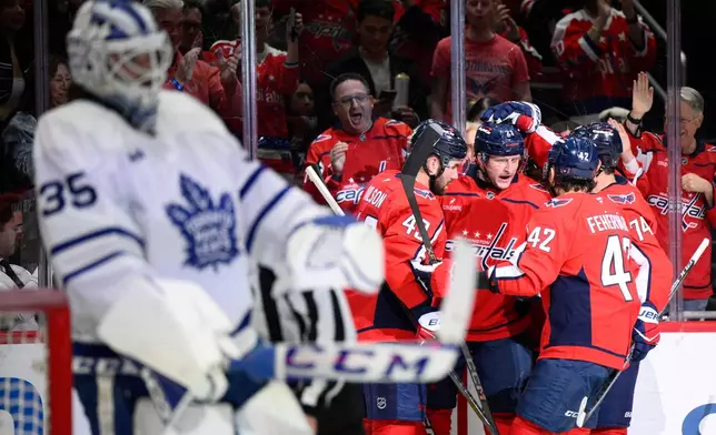 Washington Capitals center Aliaksei Protas celebrates his goal with teammates during the first period of an NHL hockey game against Toronto Maple Leafs goaltender Dennis Hildeby (35), Thursday, Dec. 18, 2025, in Washington. (AP Photo/Nick Wass)