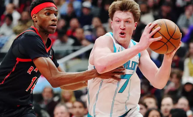 Charlotte Hornets' Kon Knueppel (7) drives past Toronto Raptors' Ja'Kobe Walter (14) during first half NBA basketball action in Toronto on Friday, Dec. 5, 2025. (Frank Gunn/The Canadian Press via AP)