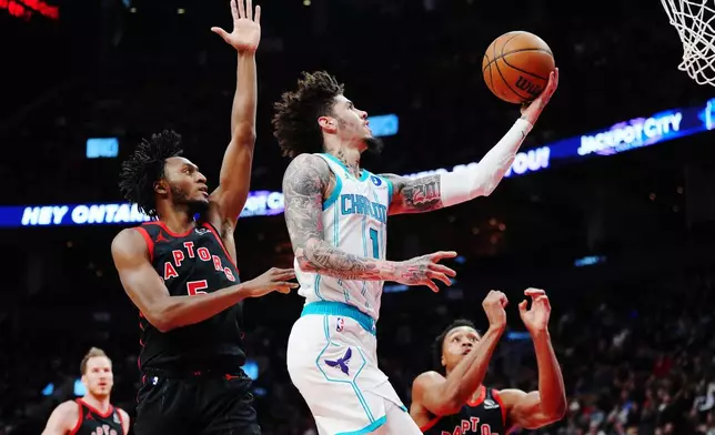 Charlotte Hornets' Lamelo Ball (1) scores past Toronto Raptors' Immanuel Quickley, front left, during first-half NBA basketball game action in Toronto, Friday, Dec. 5, 2025. (Frank Gunn/The Canadian Press via AP)