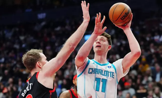 Charlotte Hornets' Ryan Kalkbrenner (11) shoots over Toronto Raptors' Jakob Poeltl (19) during first half NBA basketball action in Toronto on Friday, Dec. 5, 2025. (Frank Gunn/The Canadian Press via AP)