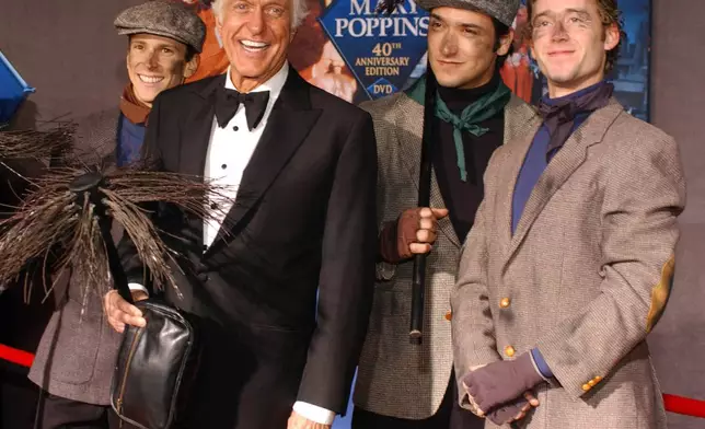 FILE - Dick Van Dyke poses with chimney sweeps during arrivals to the 40th anniversary and re-premiere of Mary Poppins at the El Capitan Theatre in Los Angeles, Tuesday, Nov. 30, 2004. (AP Photo/Ann Johansson, File)