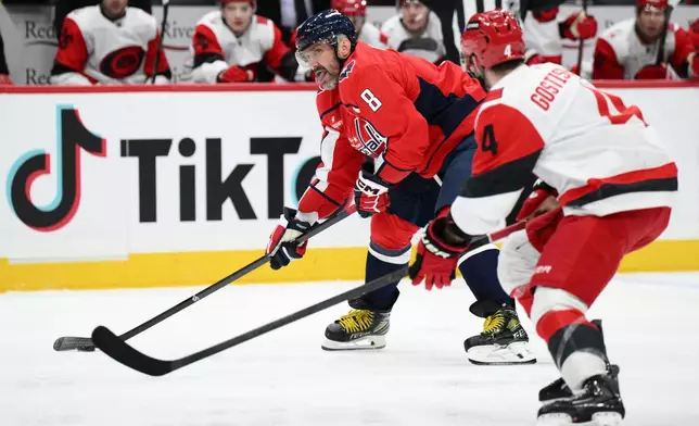Washington Capitals left wing Alex Ovechkin (8) skates with the puck against Carolina Hurricanes defenseman Shayne Gostisbehere (4) during the first period of an NHL hockey game, Thursday, Dec. 11, 2025, in Washington. (AP Photo/Nick Wass)