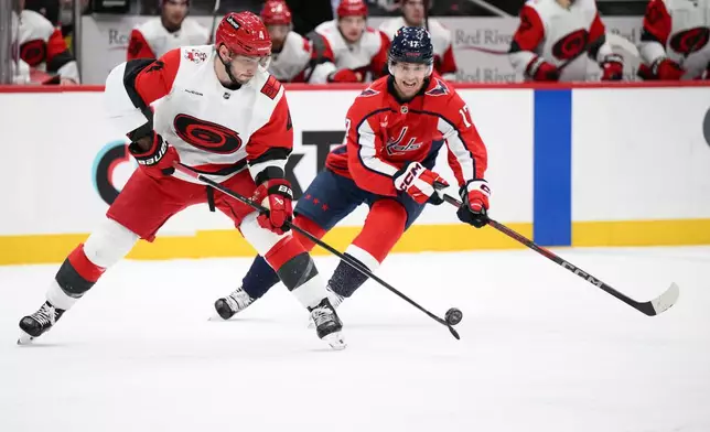 Carolina Hurricanes defenseman Shayne Gostisbehere (4) and Washington Capitals center Dylan Strome (17) battle for the puck during the first period of an NHL hockey game, Thursday, Dec. 11, 2025, in Washington. (AP Photo/Nick Wass)