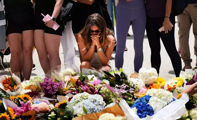 A woman kneels and prays at a flower memorial to shooting victims outside the Bondi Pavilion at Sydney's Bondi Beach, Monday, Dec. 15, 2025, a day after a shooting. (AP Photo/Mark Baker)