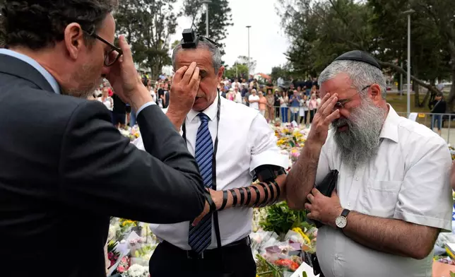 Israeli Ambassador to Australia Amir Maimon, center, prays at a floral memorial near the Bondi Pavilion at Bondi Beach on Tuesday, Dec. 16, 2025, following Sunday's shooting in Sydney, Australia. (AP Photo/Mark Baker)