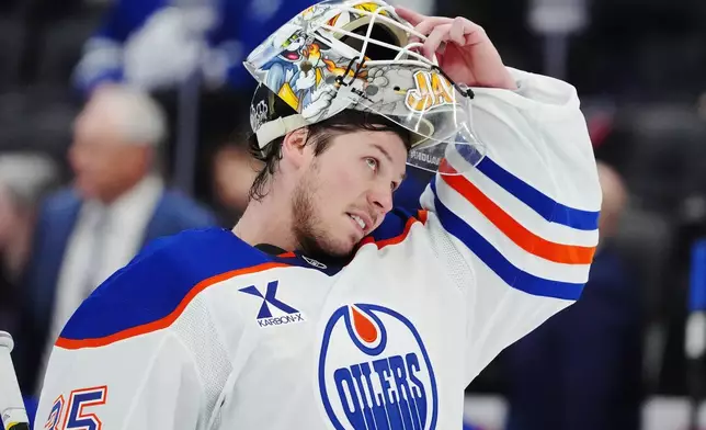Edmonton Oilers goaltender Tristan Jarry (35) adjusts his mask during second period NHL hockey action in Toronto on Saturday, Dec. 13, 2025. (Frank Gunn/The Canadian Press via AP)
