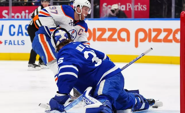 Edmonton Oilers' Connor McDavid (97) scores on Toronto Maple Leafs goaltender Dennis Hildeby during the first period of an NHL hockey game in Toronto, Saturday, Dec. 13, 2025. (Frank Gunn/The Canadian Press via AP)
