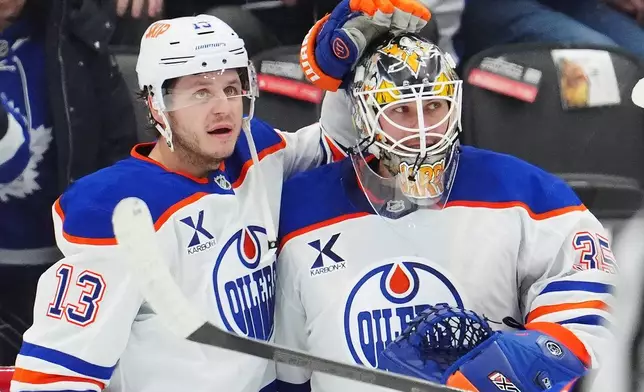 Edmonton Oilers' Connor McDavid, left to right, goaltender Tristan Jarry (35) and goaltender Calvin Pickard (30) celebrate after defeating the Toronto Maple Leafs in an NHL hockey game in Toronto on Saturday, Dec. 13, 2025. (Frank Gunn/The Canadian Press via AP)