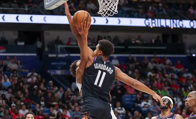 New Orleans Pelicans guard Jordan Poole, center left, goes up to shoots a layup against Phoenix Suns forward Oso Ighodaro (11) in the first half of an NBA basketball game Friday, Dec. 26, 2025, in New Orleans. (AP Photo/Peter Forest)