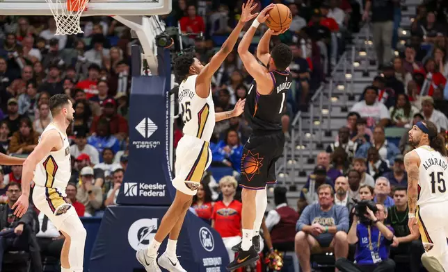 Phoenix Suns guard Devin Booker (1) shoots a jumper over New Orleans Pelicans forward Trey Murphy III, center left, in the first half of an NBA basketball game Friday, Dec. 26, 2025, in New Orleans. (AP Photo/Peter Forest)