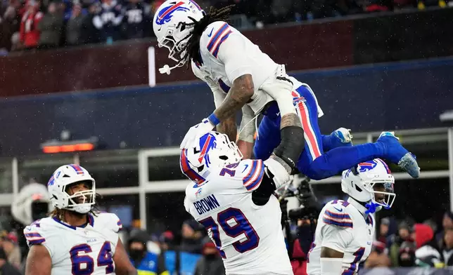 Buffalo Bills running back James Cook III, top, celebrates with offensive tackle Spencer Brown (79) after scoring against the New England Patriots during the second half of an NFL football game in Foxborough, Mass., Sunday, Dec. 14, 2025. (AP Photo/Robert F. Bukaty)
