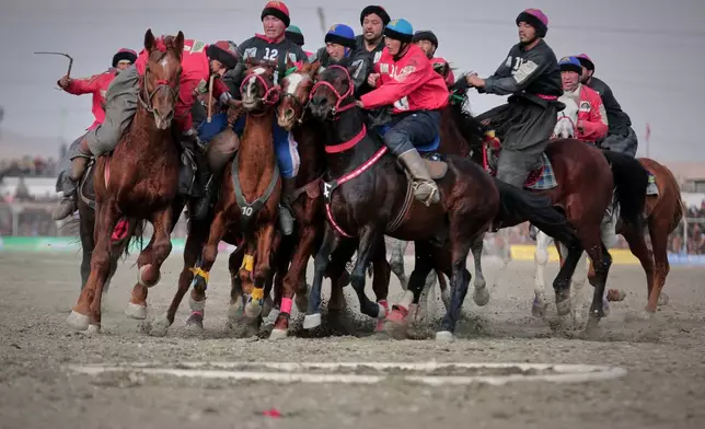 Riders from the Sar-e-Pul and Badakhshan teams compete in the final of Afghanistan's annual buzkashi tournament, a traditional equestrian sport in which riders score points using a fake goat carcass, on the outskirts of Kabul, Afghanistan, Monday, Dec. 22, 2025. (AP Photo)