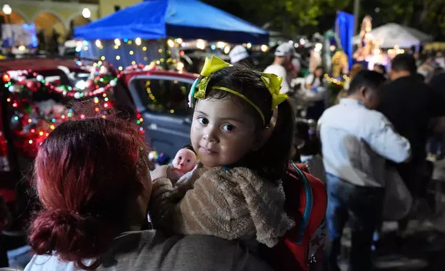 A little girl holds a doll, one of many gifts distributed at dozens of open-air altars to the Virgin Mary, as Nicaraguan parishioners of St. John Bosco Catholic Church celebrate the Dec. 8 feast of the Immaculate Conception, Sunday, Dec. 7, 2025, in Miami. (AP Photo/Rebecca Blackwell)