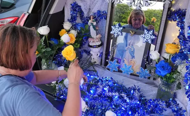 Egda Lee sets up an altar centered around a picture of the Virgin Mary which she carried with her when she crossed the U.S. border in 1984 pregnant with her son Neri Flores, as Nicaraguan parishioners of St. John Bosco Catholic Church celebrate the Dec. 8 feast of the Immaculate Conception, Sunday, Dec. 7, 2025, in Miami. (AP Photo/Rebecca Blackwell)
