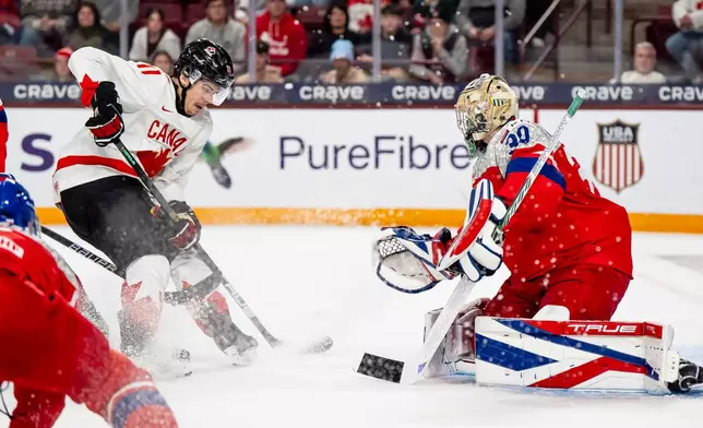 Canada's Tij Iginla (11) attacks the net defended by Czechia goaltender Michal Orsulak (30) during second-period IIHF World Junior Championship hockey game action in Minneapolis, Friday, Dec. 26, 2025. (Christopher Katsarov/The Canadian Press via AP)