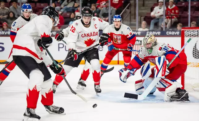 Canada's Michael Misa, front left, attacks Czechia goaltender Michal Orsulak (30) while Canada's Porter Martone (22) stands in front of the net during second-period IIHF World Junior Championship hockey game action in Minneapolis, Friday, Dec. 26, 2025. (Christopher Katsarov/The Canadian Press via AP)