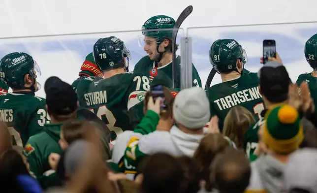 Minnesota Wild defenseman Quinn Hughes, center, is congratulated after scoring during the third period of an NHL hockey game against the Boston Bruins, Sunday, Dec. 14, 2025, in St. Paul, Minn. (AP Photo/Bailey Hillesheim)