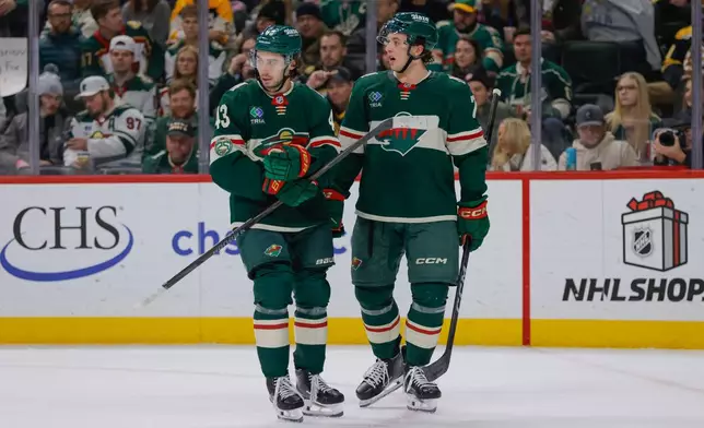 Minnesota Wild defenseman Brock Faber (7) talks with defenseman Quinn Hughes (43) during the first period of an NHL hockey game against the Boston Bruins, Sunday, Dec. 14, 2025, in St. Paul, Minn. (AP Photo/Bailey Hillesheim)