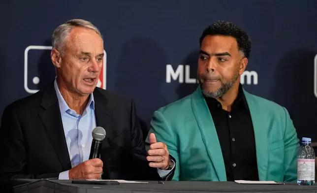 Rob Manfred, left, commissioner of Major League Baseball answers questions during a news conference as Nelson Cruz, former baseball player and general manager of the Dominican National team listens during a news conference at the MLB winter meetings, Monday, Dec. 8, 2025, in Orlando, Fla. (AP Photo/John Raoux)